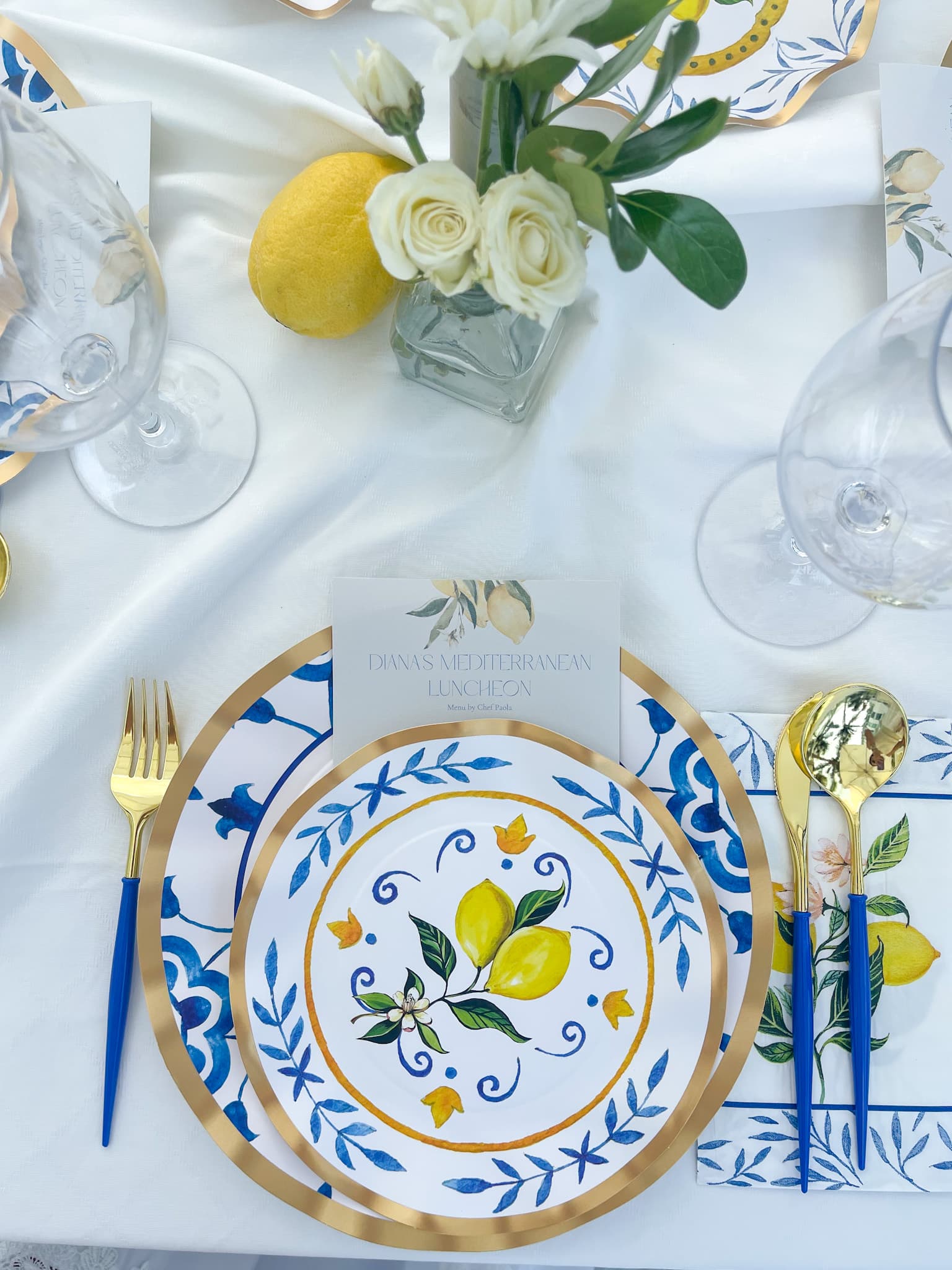 A coastal table with blue-and-yellow Mediterranean plates and lemons set by a private chef in the Hamptons