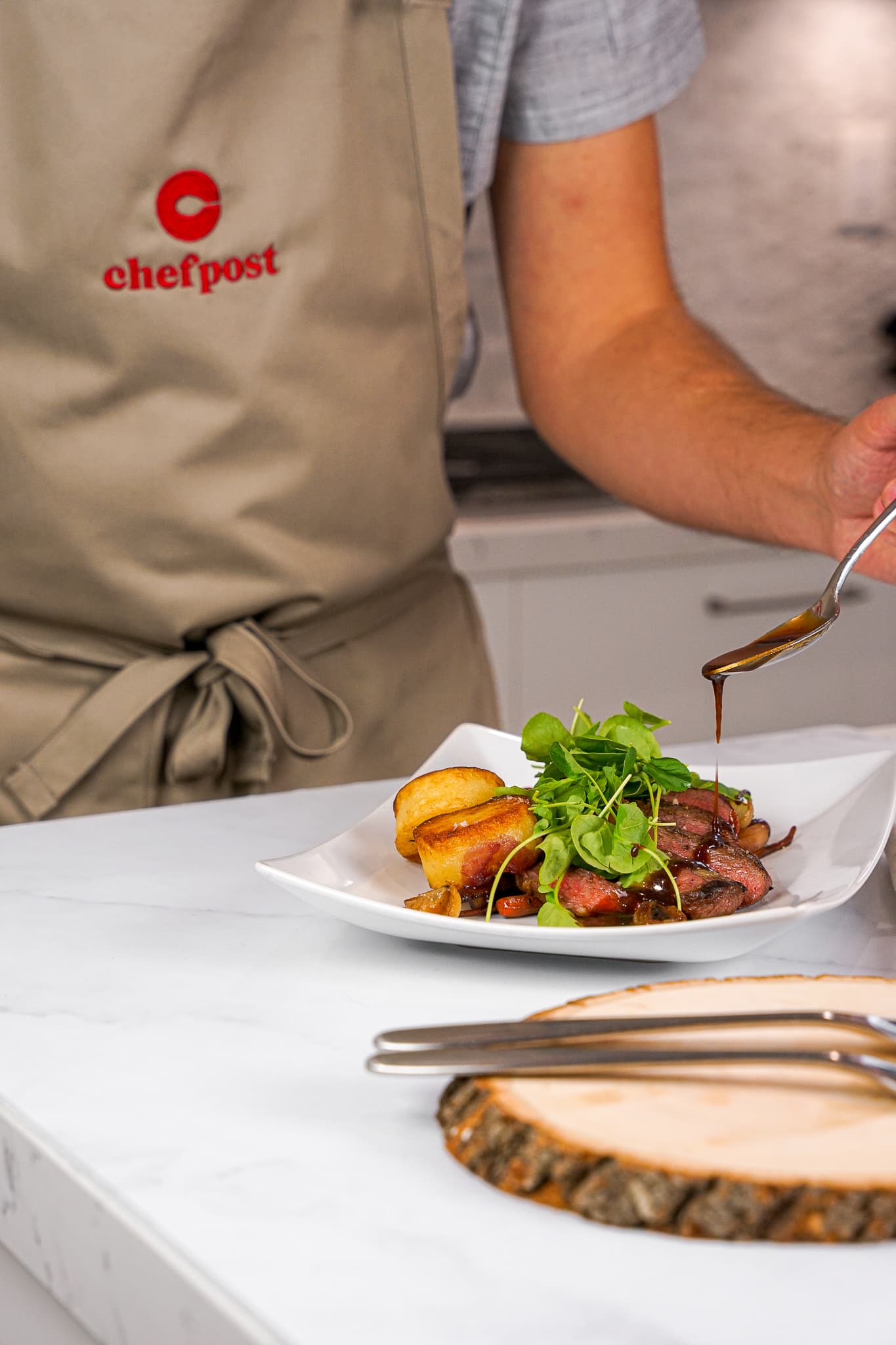 A private chef in a branded apron plating dinner in an Edgewater high-rise kitchen in Miami