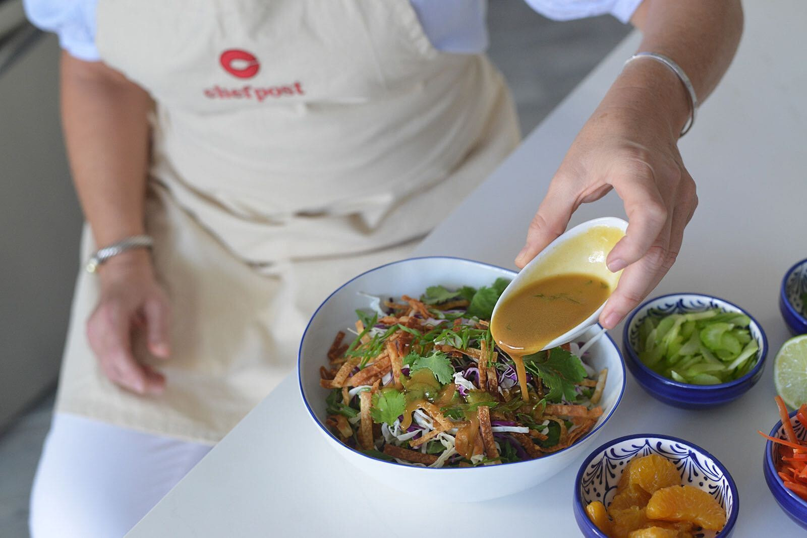 Chefpost chef in a branded apron dressing a fresh salad