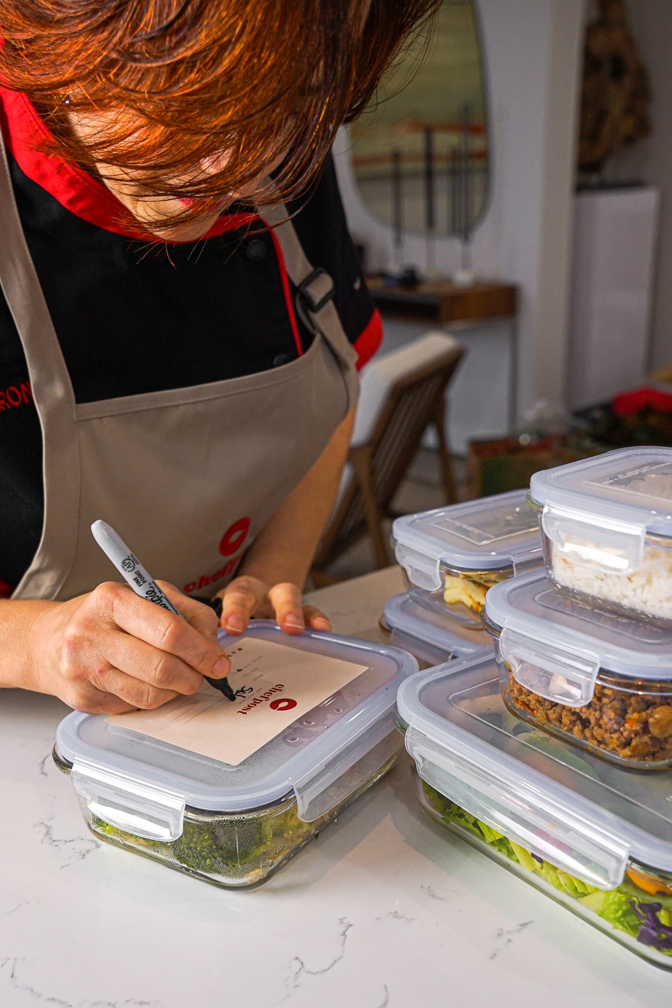 A private chef plating portioned meal-prep dishes in a Miami Beach condo kitchen