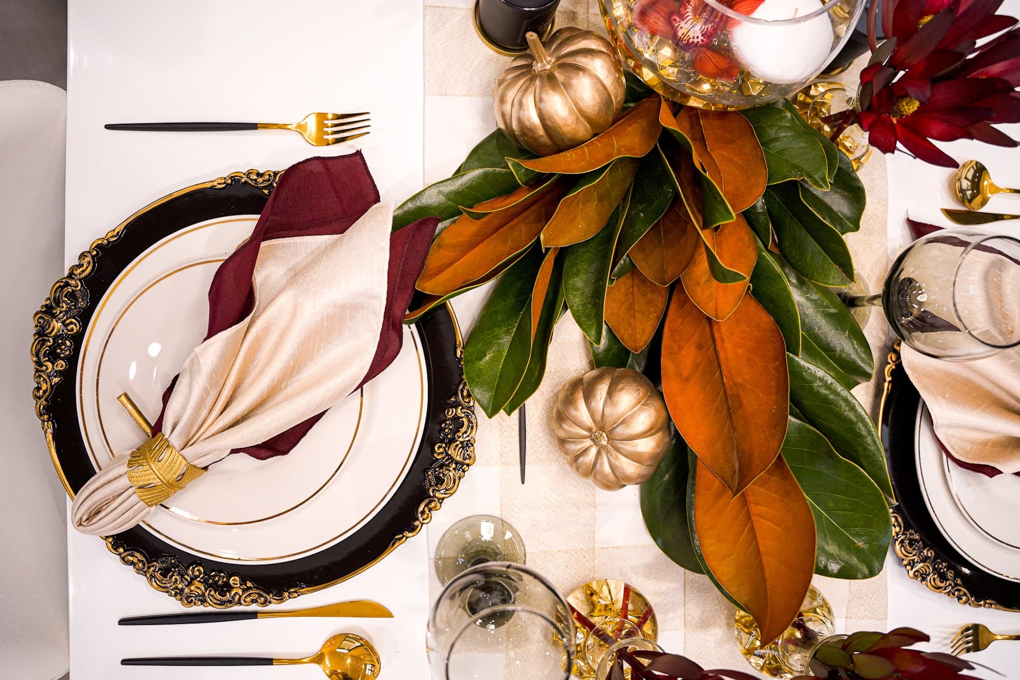 A refined table with magnolia leaves and gold details set by a private chef on Long Island